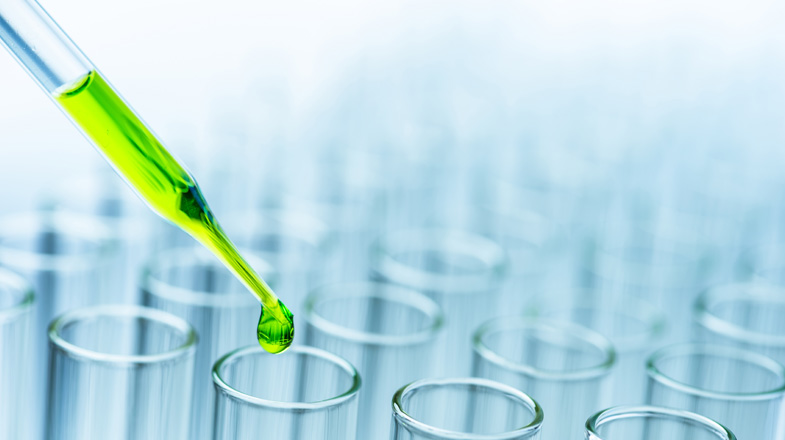 Close-Up of green liquid pouring from pipette in test tubes