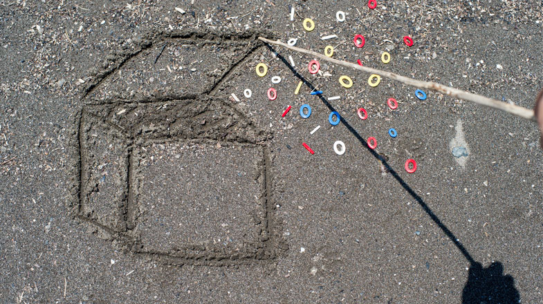 a 3D box drawn in the sand with a wooden stick