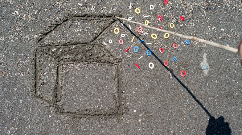 a 3D box drawn in the sand with a wooden stick