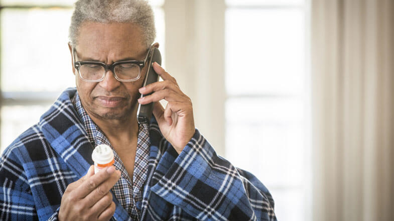 elderly man reading prescription bottle while on the phone, thumbnail