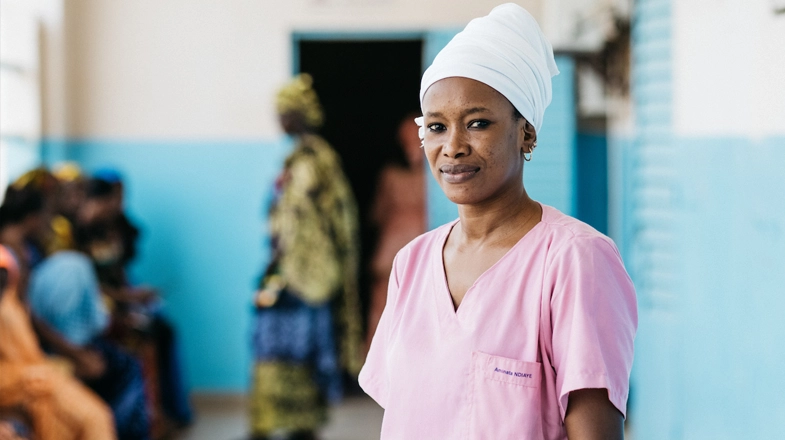 A healthcare provider smiles while standing in a clinic in sub-Saharan Africa.