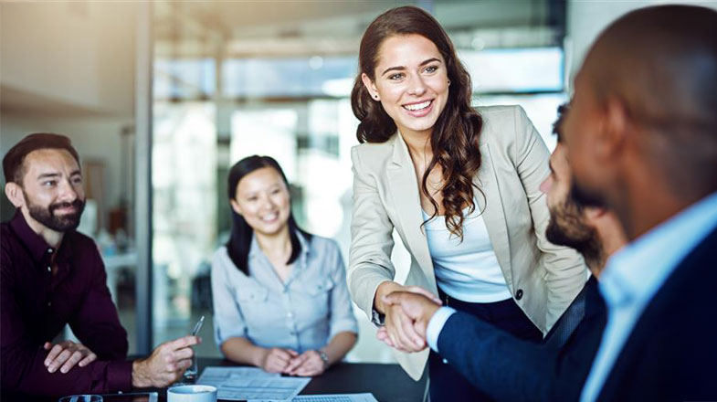 Photograph of business colleagues in a meeting as two people shake hands across a table