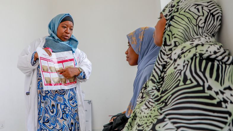 Photograph of a female health worker teaching two young women
