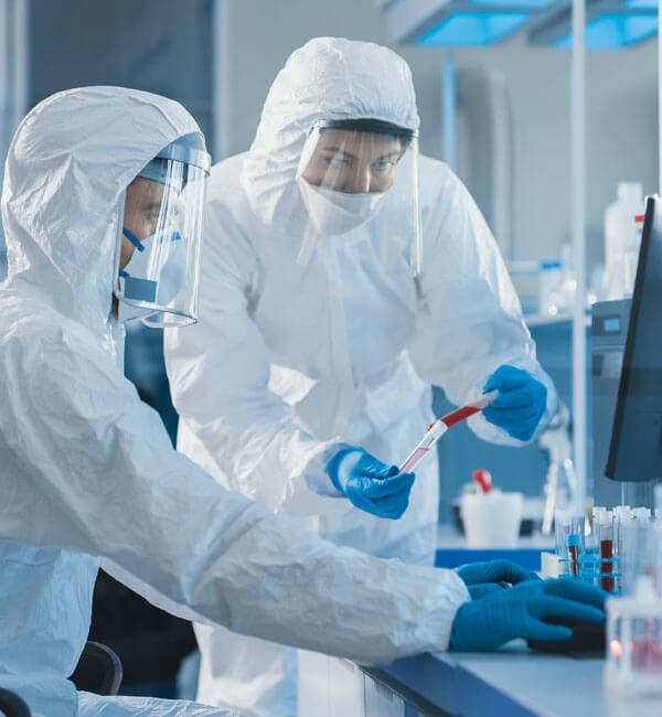 Photograph of two scientists in protective suits working with test samples in a lab