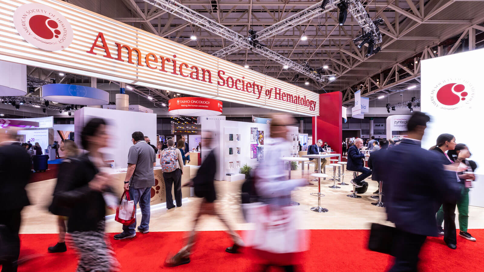 people walking by in front of the American Society of Hematology booth