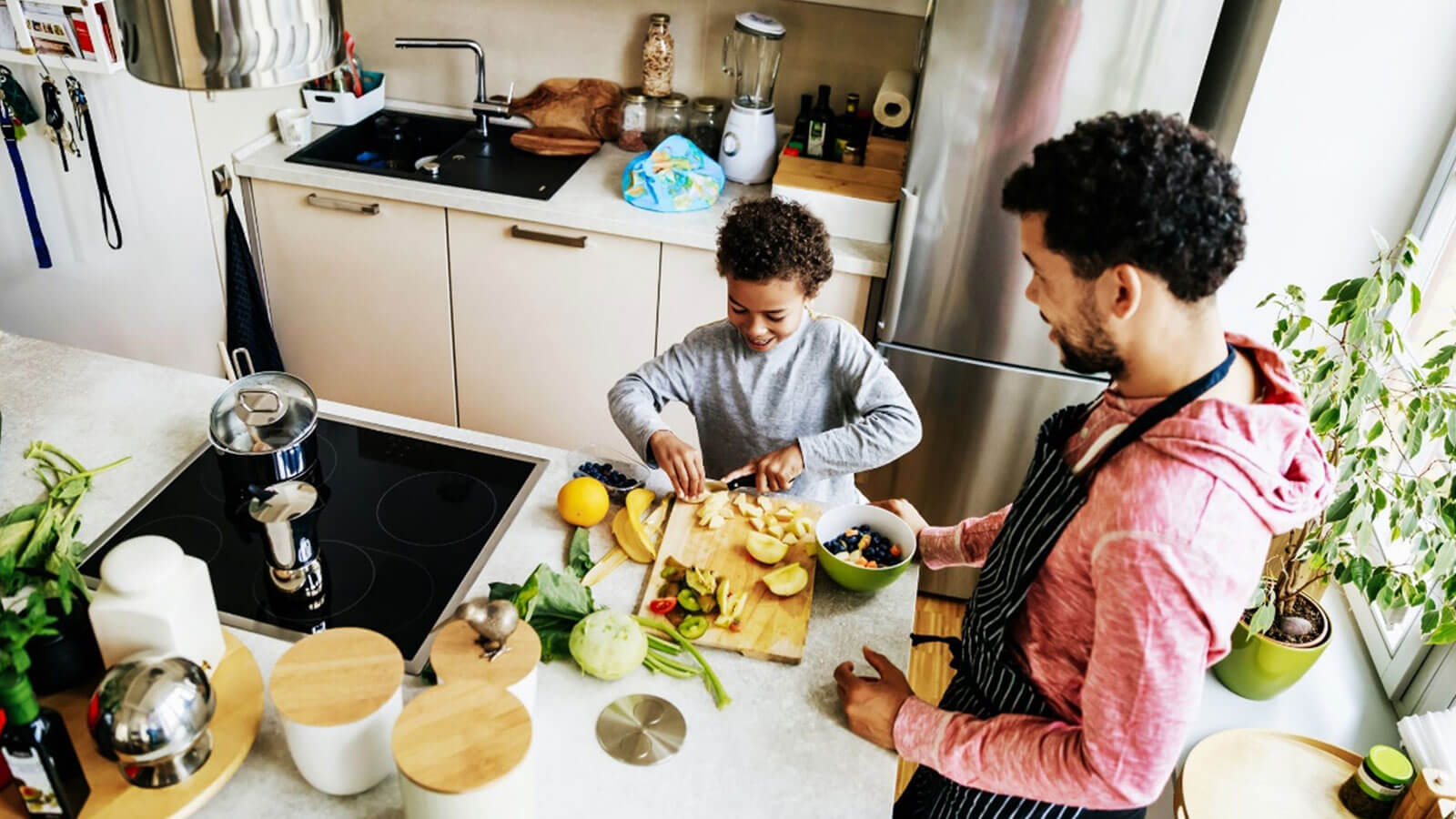Father and son chopping up fruit in a kitchen