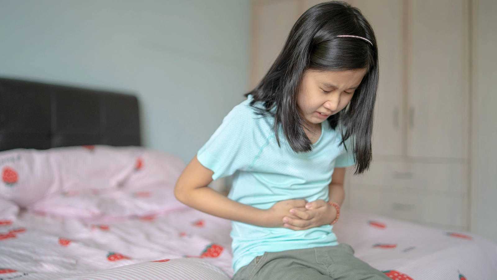 image of child holding her stomach in pain