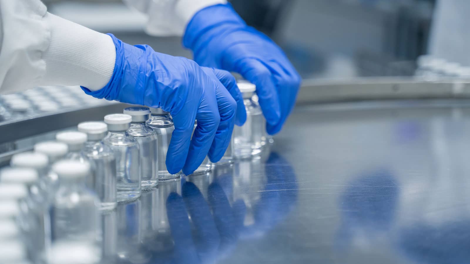 Detail of hands working in pharmaceutical factory manufacturing sterile bottles