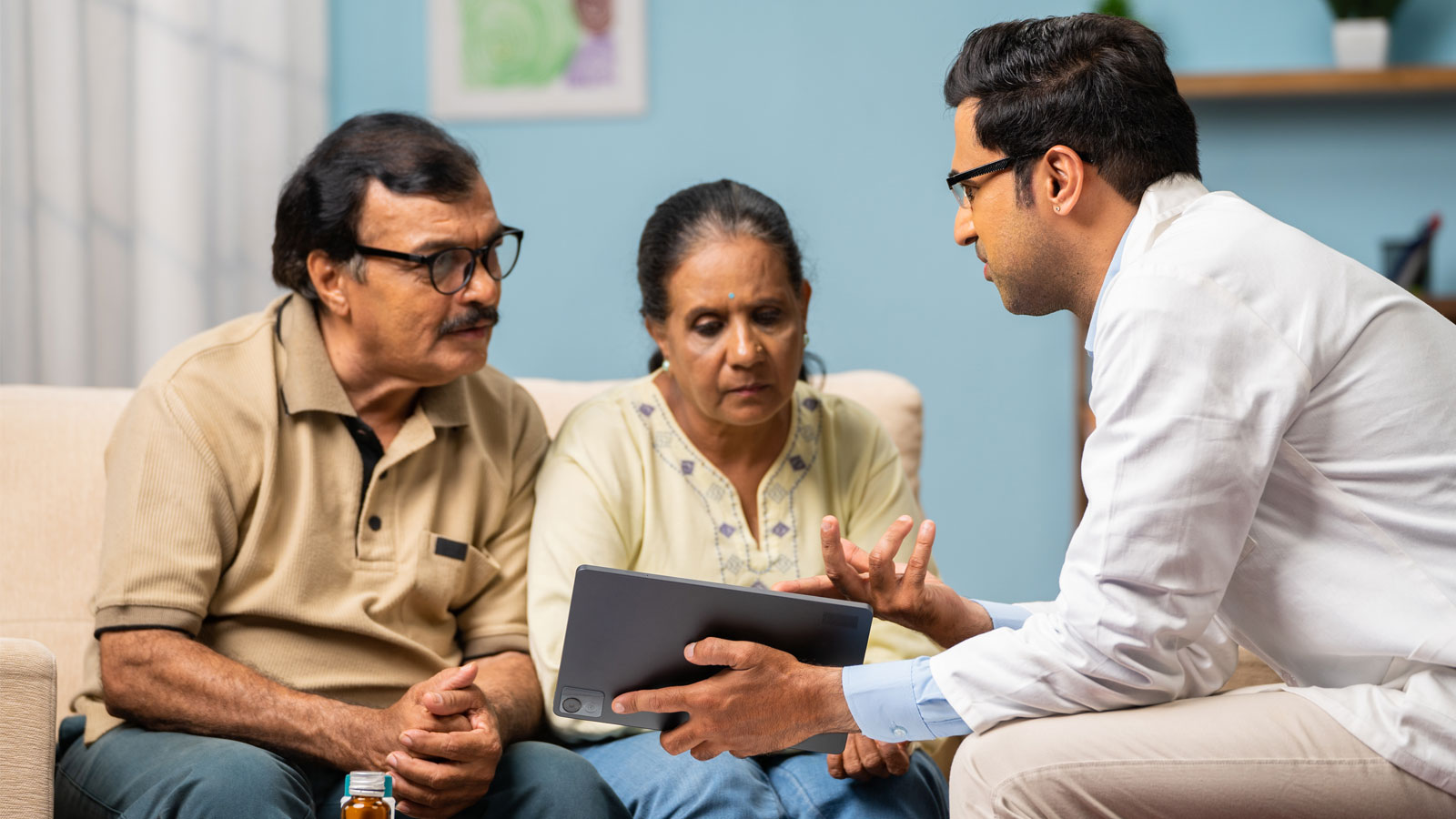 Doctor explaining from digital tablet to senior couple about medical report at home