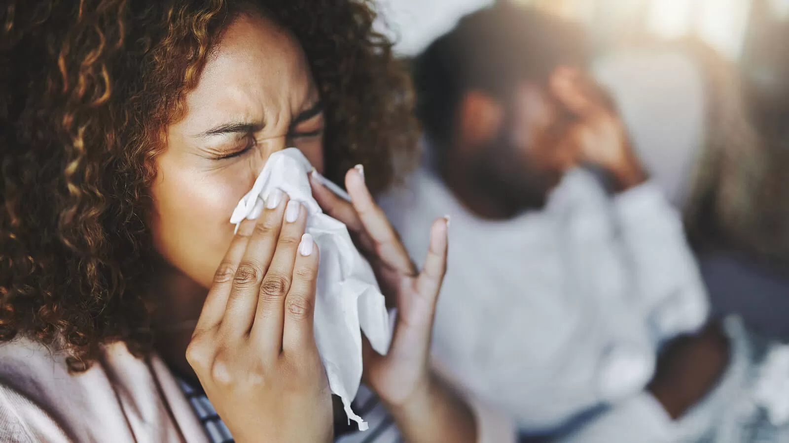 Woman sneezing into tissue