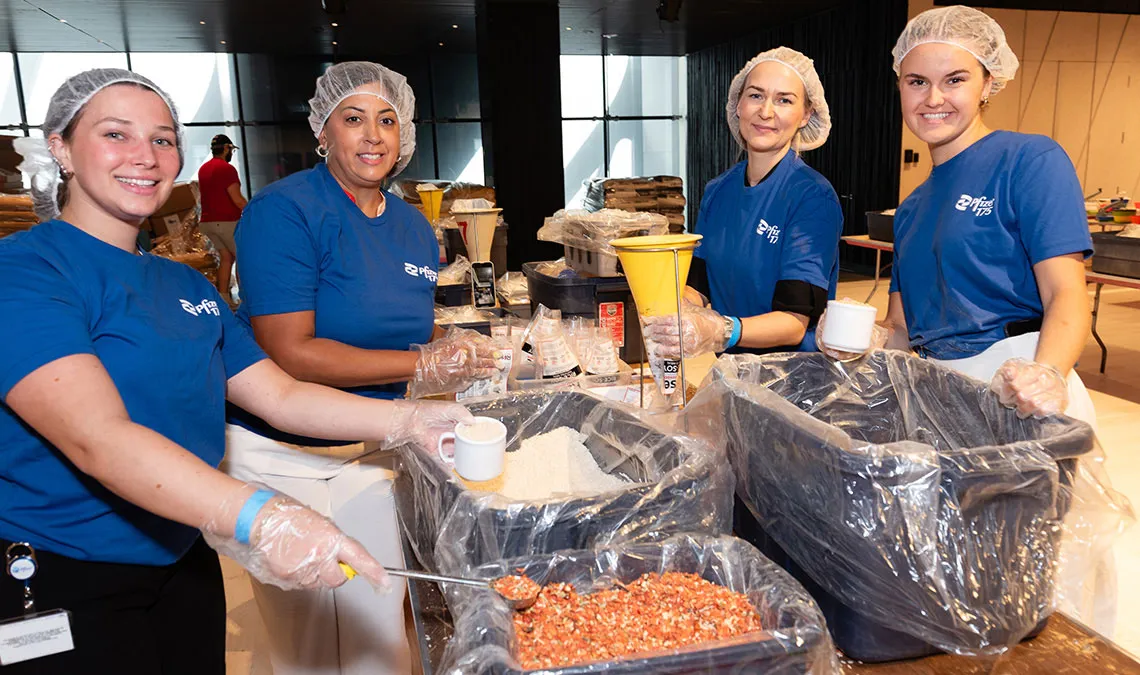 group photo new york pfizer offices volunteers preparing meals smiling at the camera