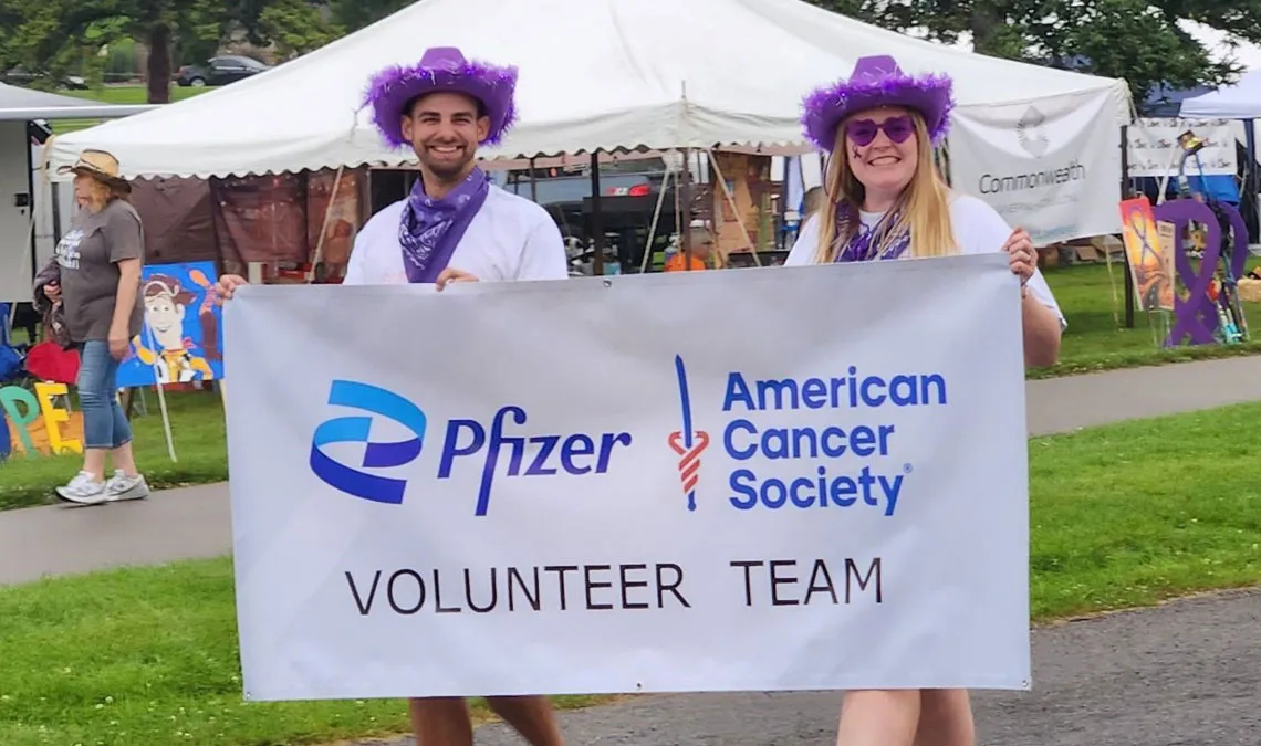 man and woman volunteers holding a banner from American cancer society