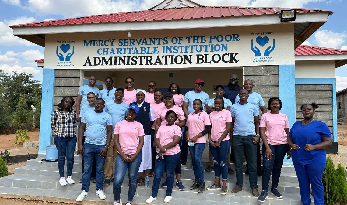 people from Kenya standing outside of mercy servants of the poor building