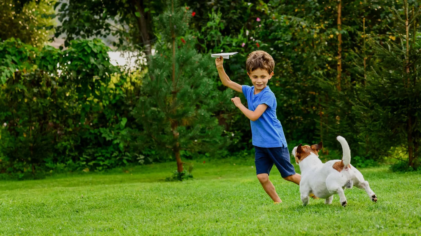 Upfront boy playing in backyard with dog