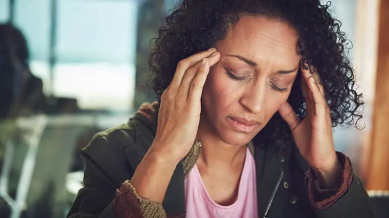 Photograph of a person indoors holding their head with both hands, looking stressed thumbnail