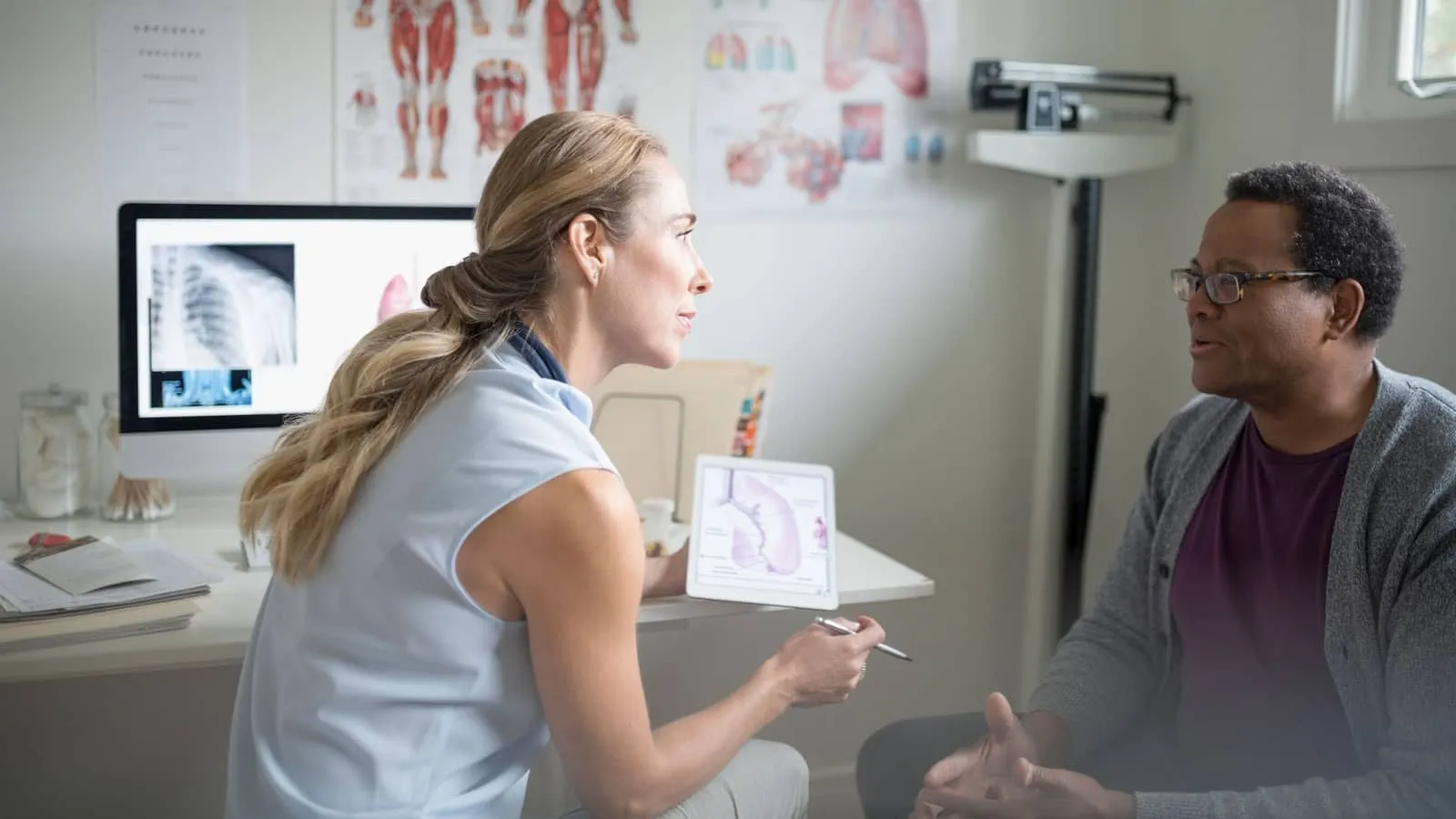 Photograph of a doctor explaining a medical diagram to a seated patient in an exam room