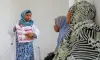 Photograph of a female health worker teaching two seated young women