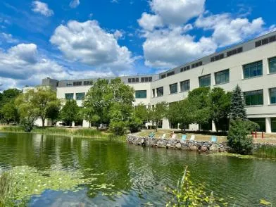Photo of Andover, Massachusetts Research Site office building beside a pond under a bright blue sky