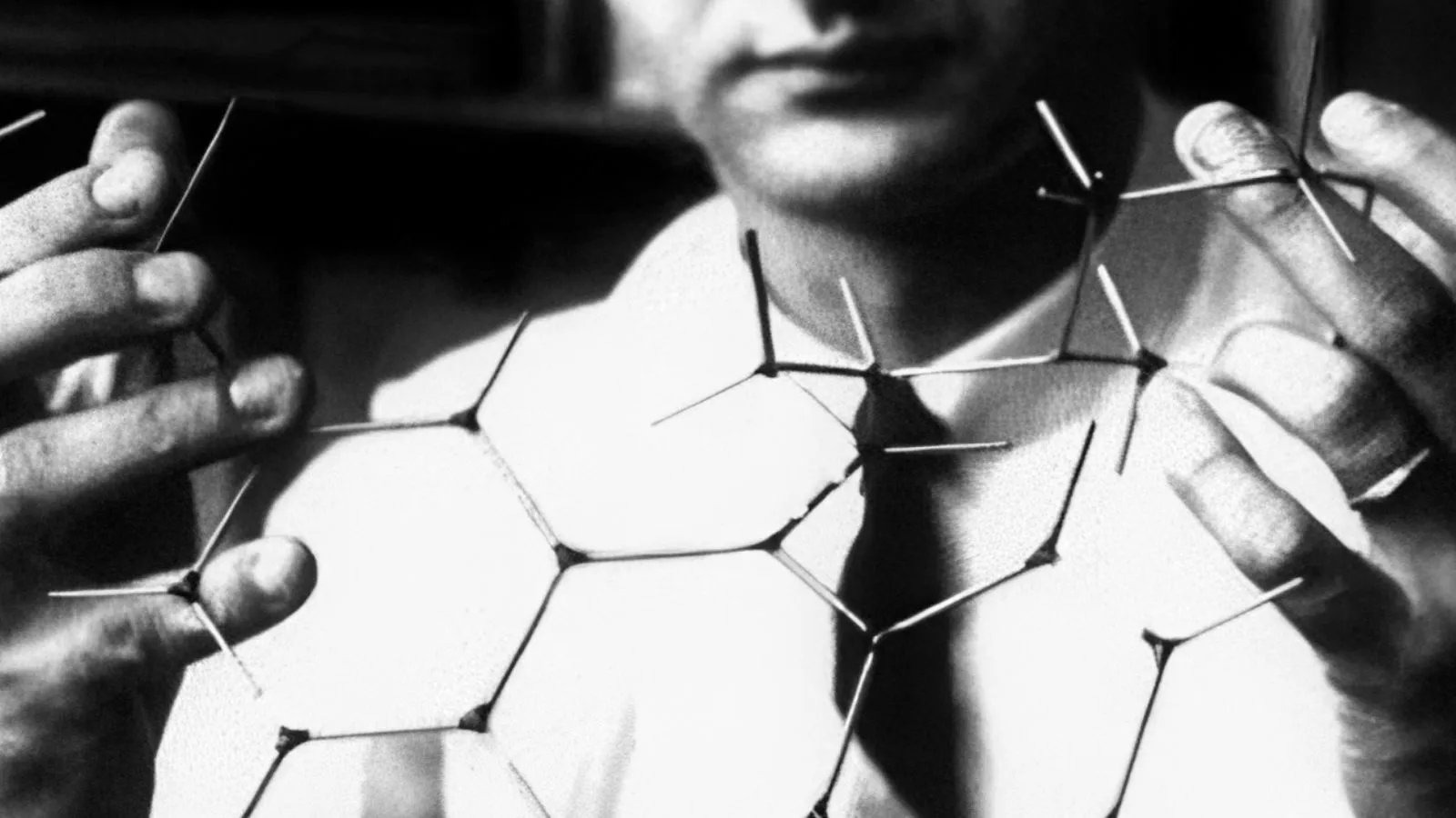 Black-and-white photo of a scientist holding a wireframe molecular model