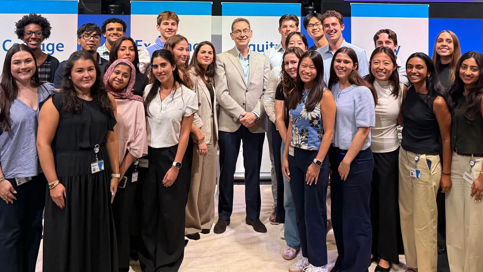 Photograph of a smiling group of young adults posing with a suited man indoors