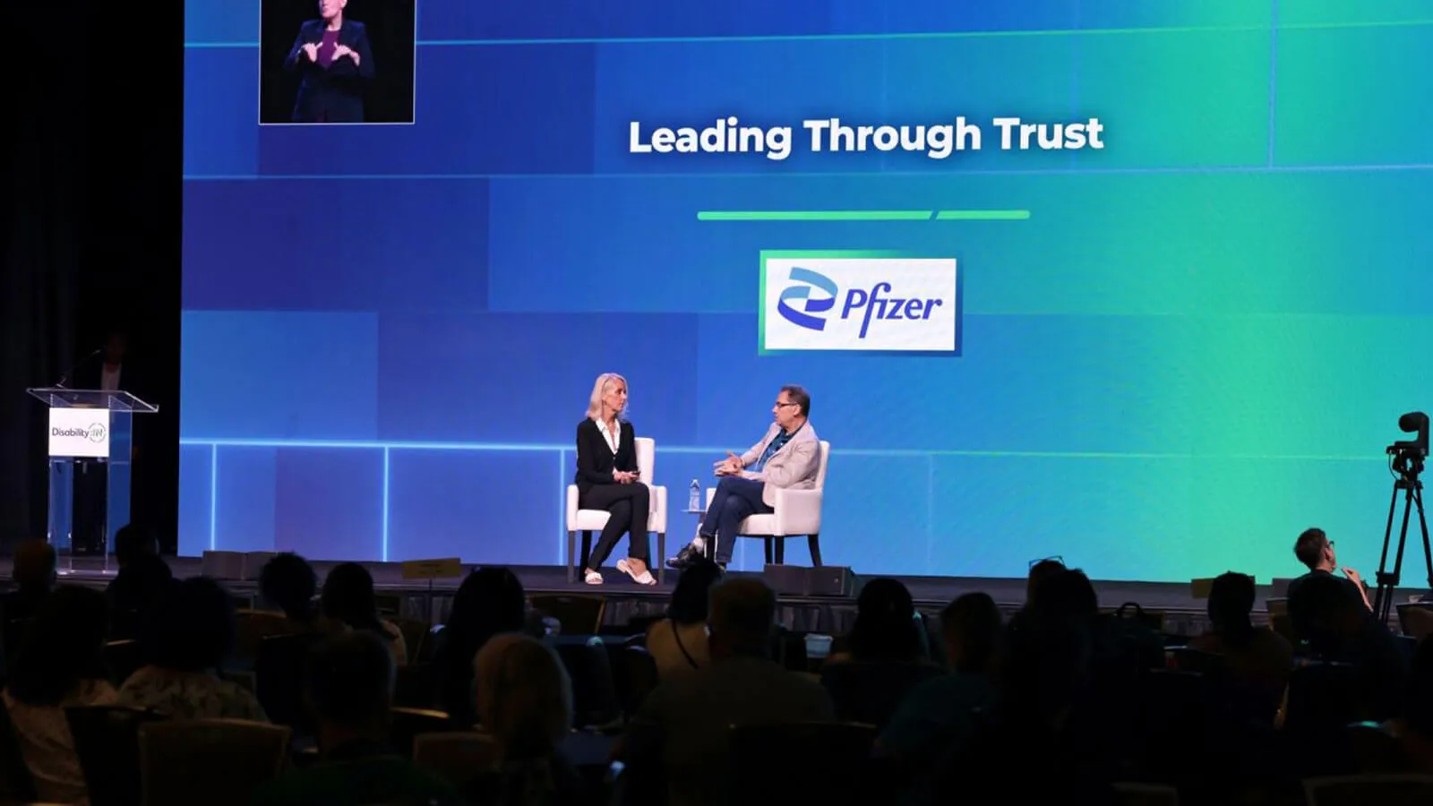 Photograph of two speakers onstage at a Pfizer event titled “Leading Through Trust”