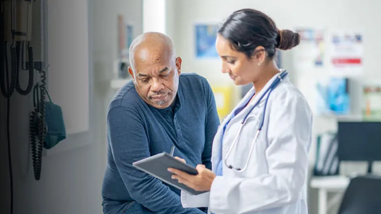 Photograph of a doctor showing a tablet to a patient in a medical office