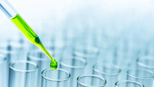 Close-Up of green liquid pouring from pipette in test tubes