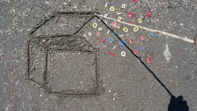 a 3D box drawn in the sand with a wooden stick