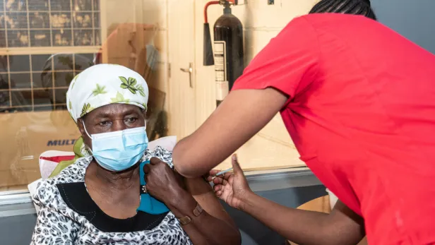 Healthcare worker gives a vaccine to community member in sub-Saharan Africa.