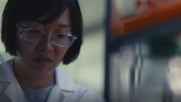 Scientist in a lab coat working beside blurred laboratory equipment thumbnail