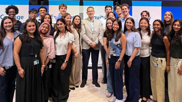 Photograph of a smiling group of young adults posing with a suited man indoors thumbnail