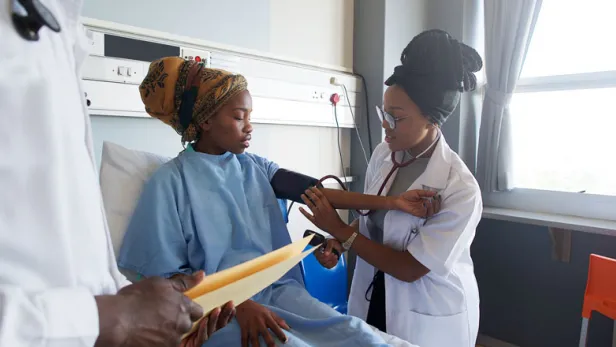 Photograph of a doctor checking a hospitalized patient's blood pressure.
