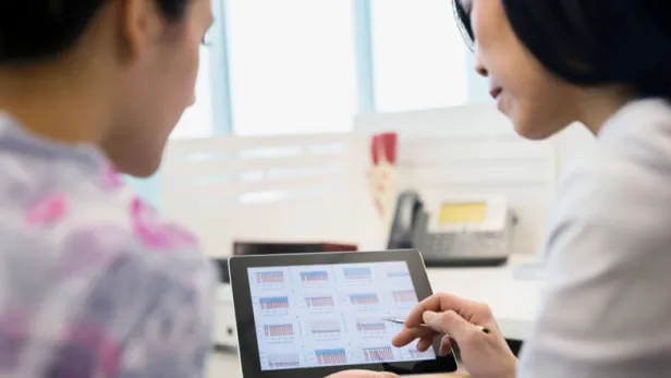 Two women review data charts on a tablet in a bright office setting thumbnail